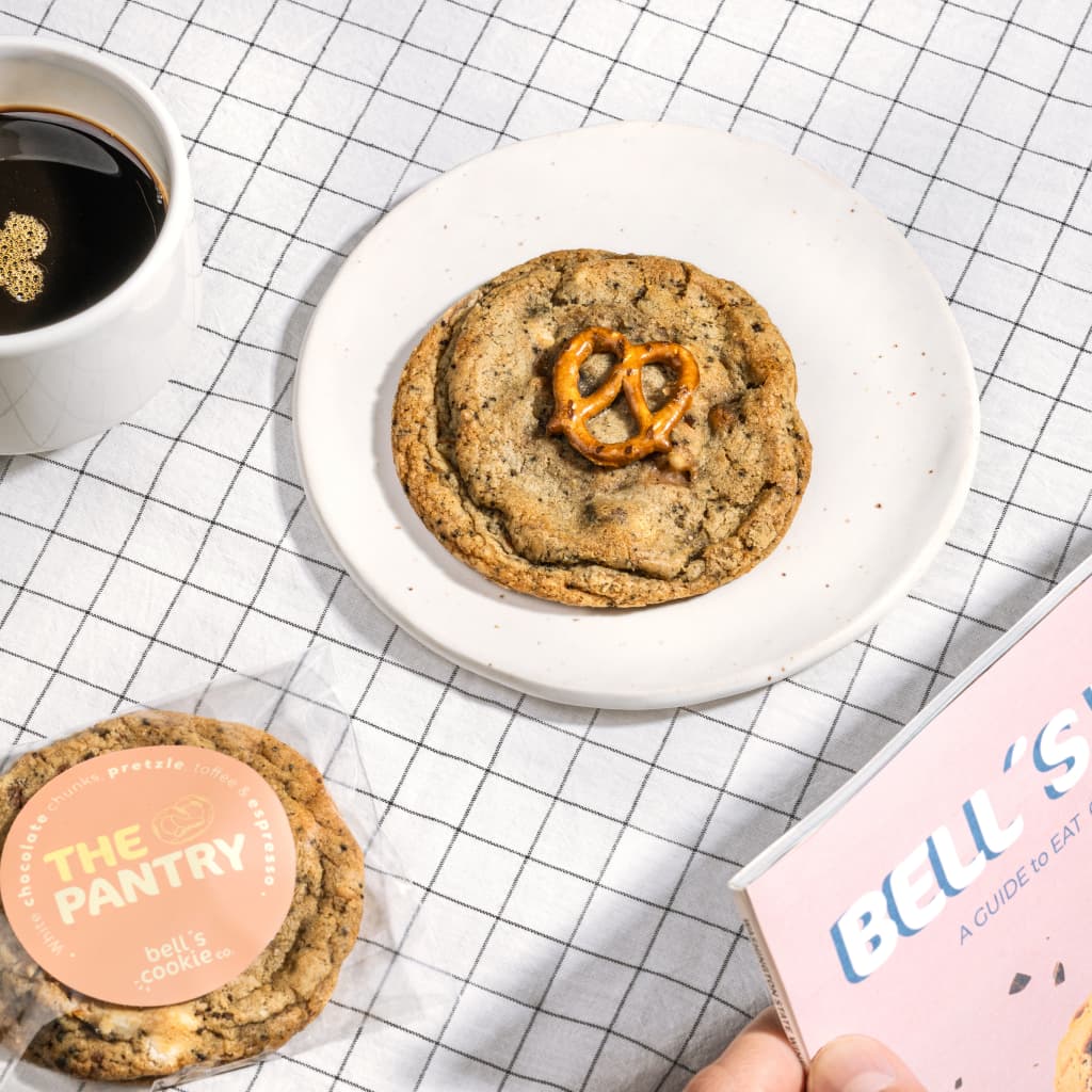 L'image montre une table avec une nappe rayée sur laquelle se trouve deux cookies de la marque Bell's Cookies, une boutique Shopify réalisée par Agence Shop.