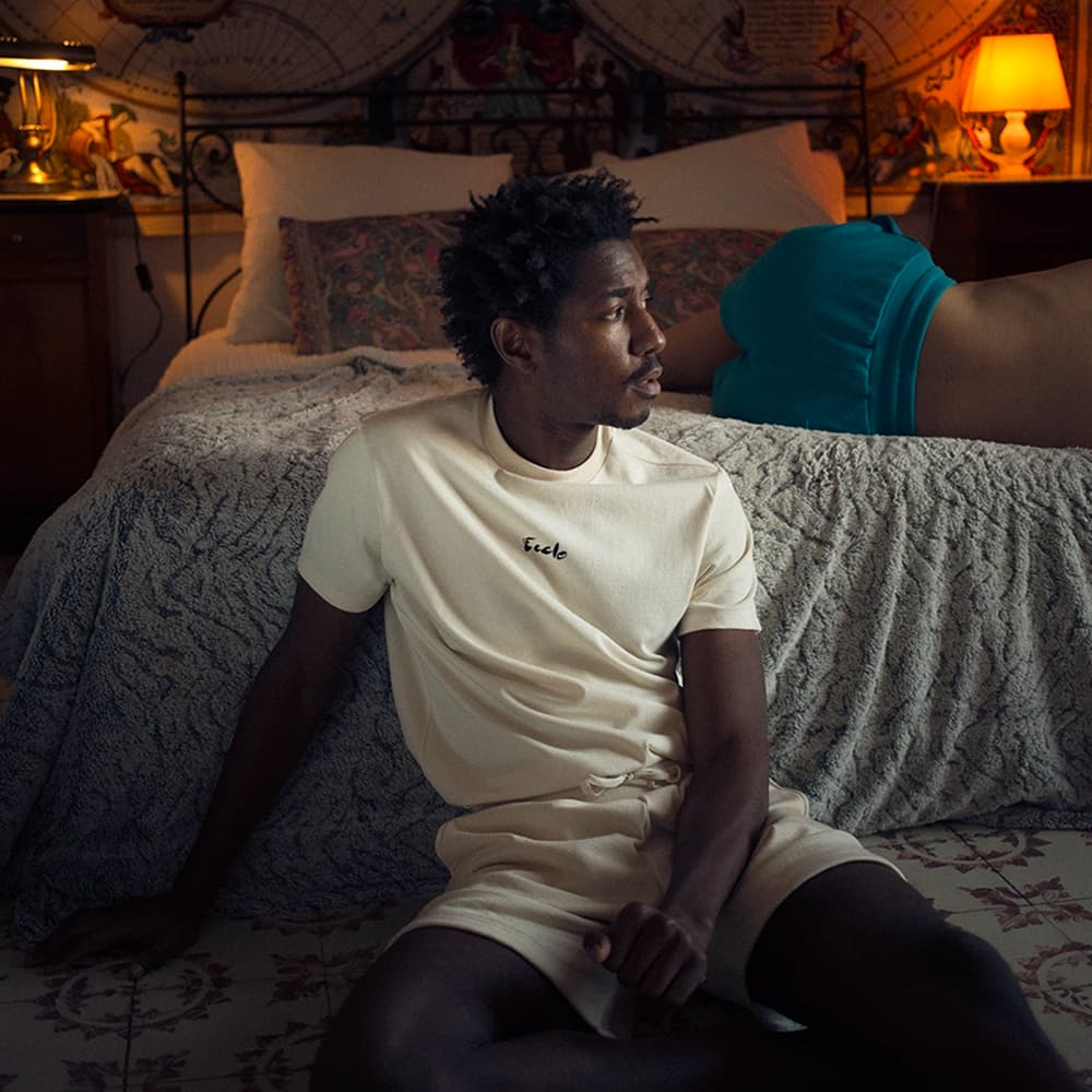 Ecclo : un homme avec un T-shirt et un short Ecclo dans une chambre d'hôtel