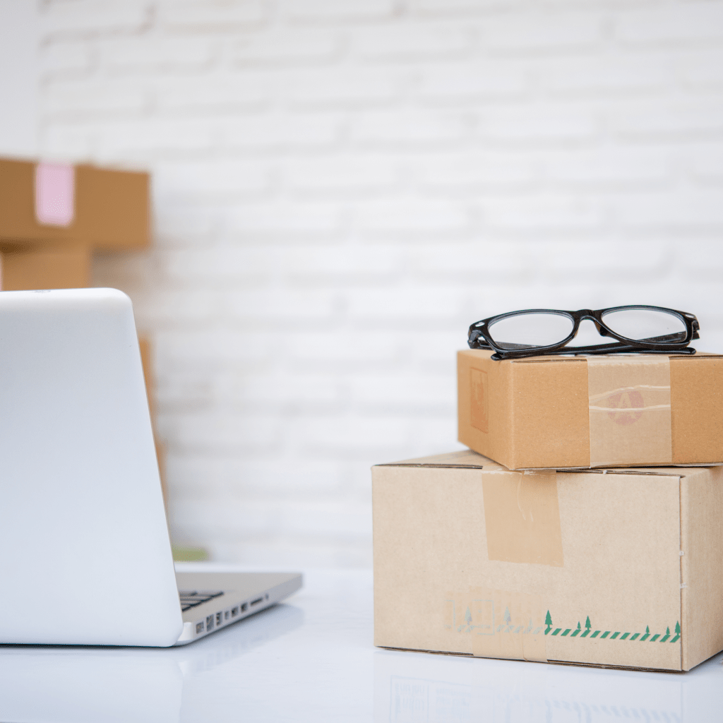 Un ordinateur sur une table, à côté de colis prêts à être envoyés