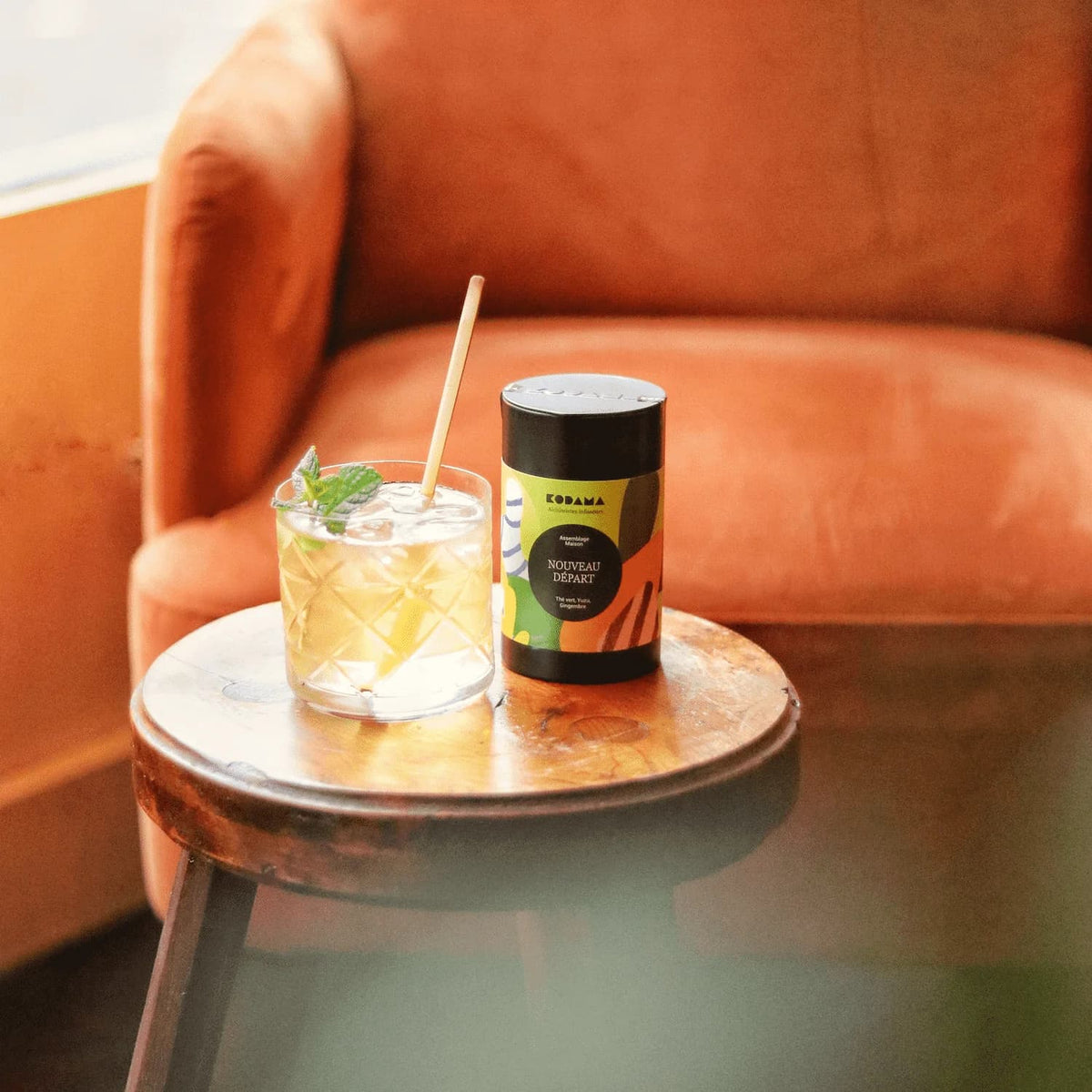 Une boîte de thé Kodama à côté d'un cocktail sur un tabouret