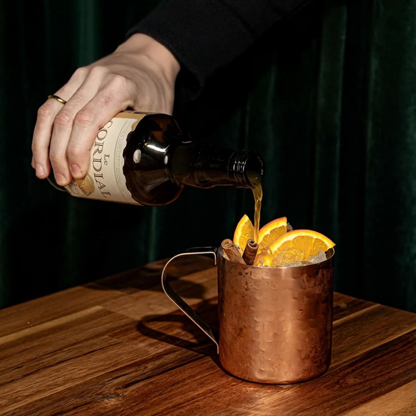 Man pouring a cordial into a cocktail glass